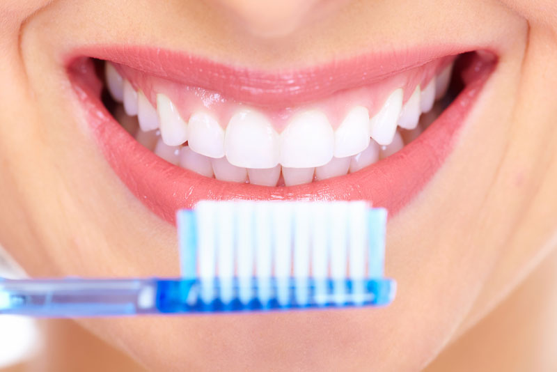 a full mouth dental implant patient smiling with a toothbrush.